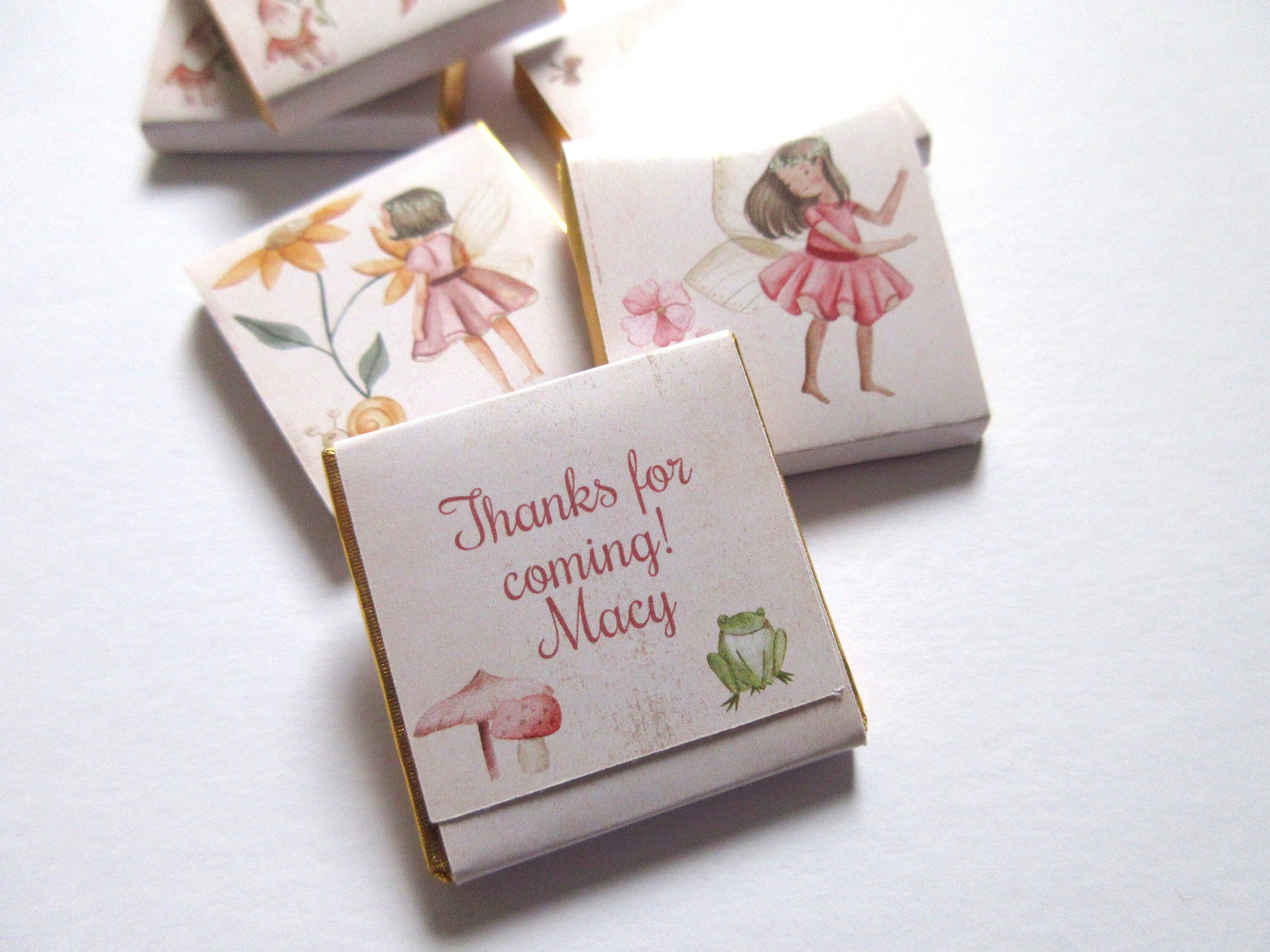 May include: White favour boxes with gold trim, featuring a fairy illustration and the text "Thanks for coming! Macy".
