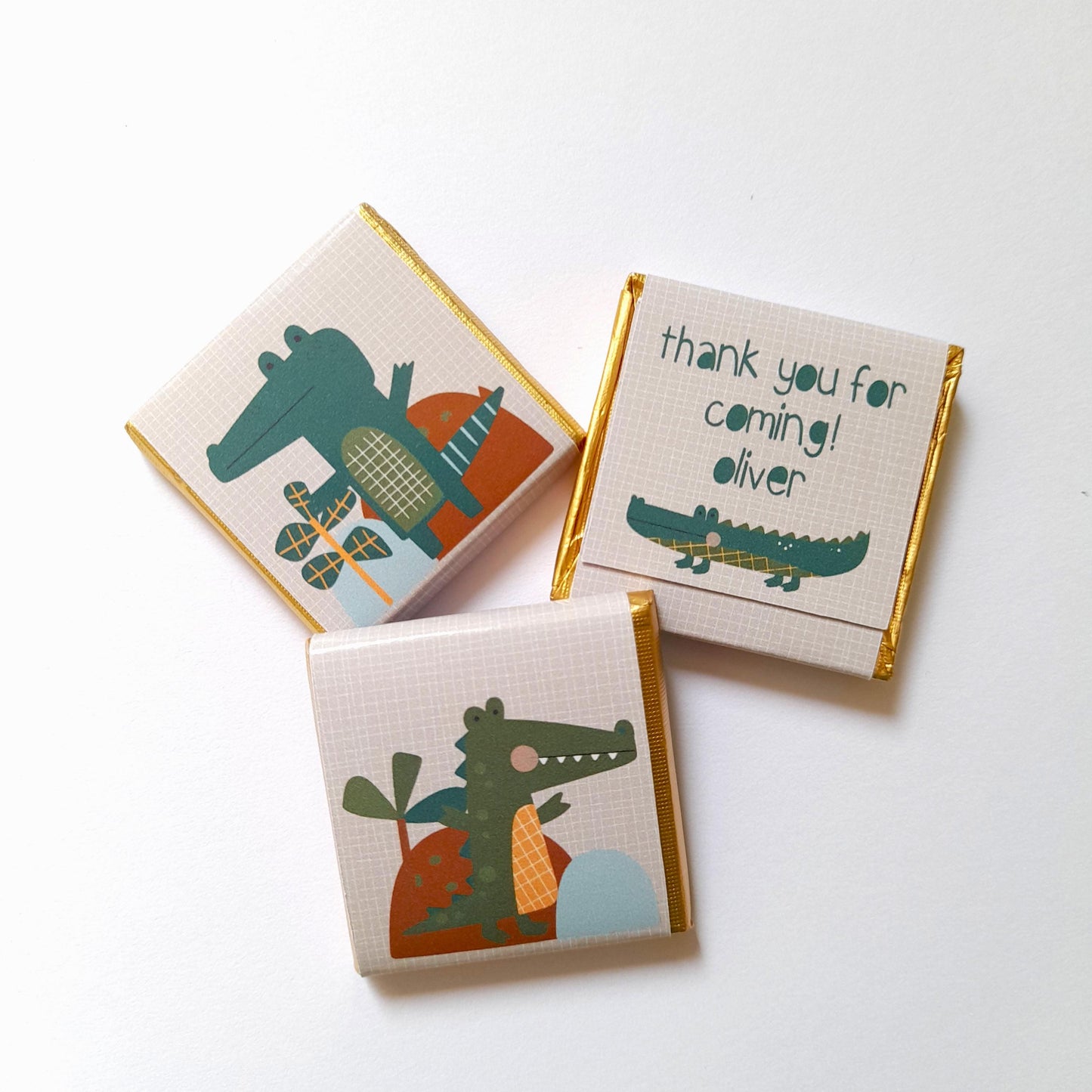 May include: Three small chocolate bars wrapped in gold foil with a green crocodile design and the text "thank you for coming! oliver".