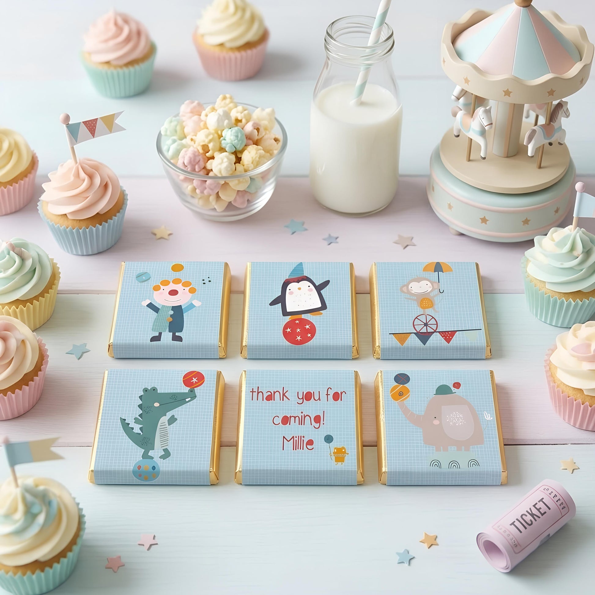 May include: A party scene with cupcakes, popcorn, and chocolate bars. The chocolate bars feature circus-themed illustrations and the text "thank you for coming! Millie". A small carousel and a bottle of milk with a straw are also present.